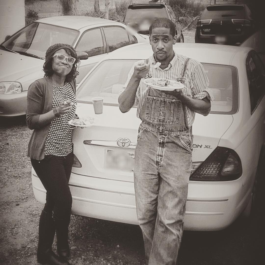 man and woman sitting in front of car eating