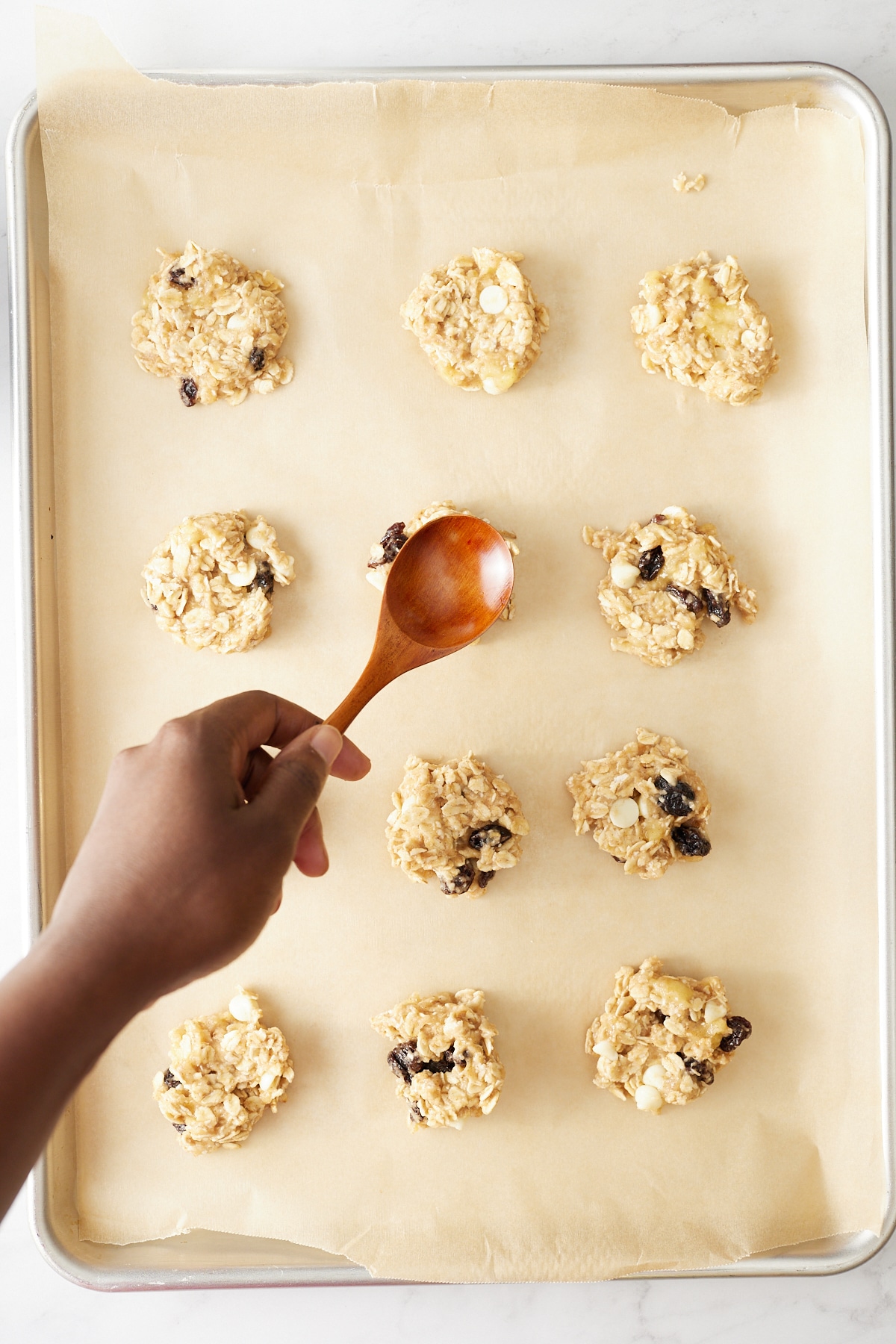 banana oatmeal breakfast cookies being flattened with a spoon on cookie sheet