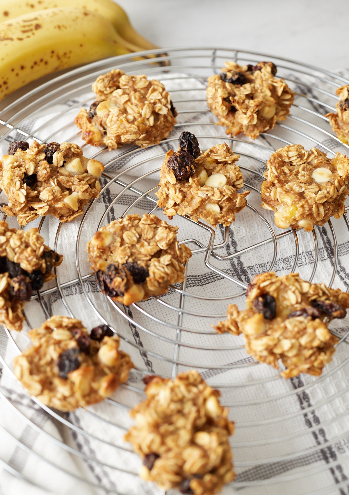 banana oatmeal breakfast cookies on wire rack with bananas in background