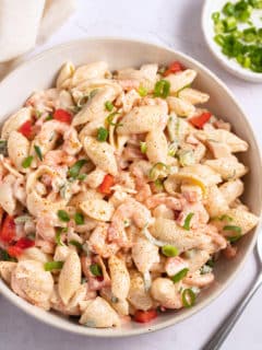 seafood salad in bowl with green onions next to the bowl