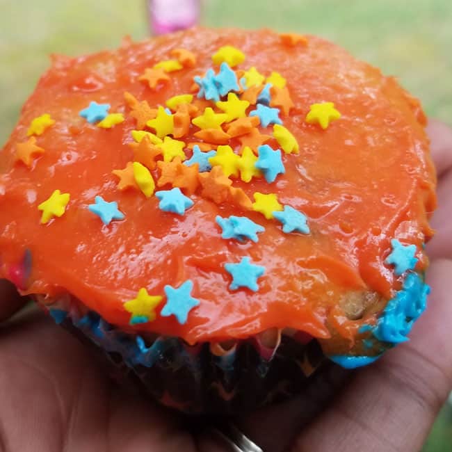 cupcake covered in orange frosting with sprinkles