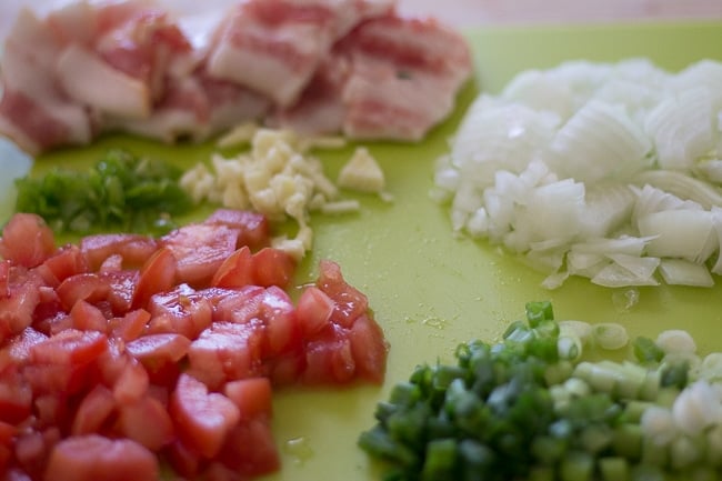 onions, tomatoes, garlic, thyme chopped on cutting board