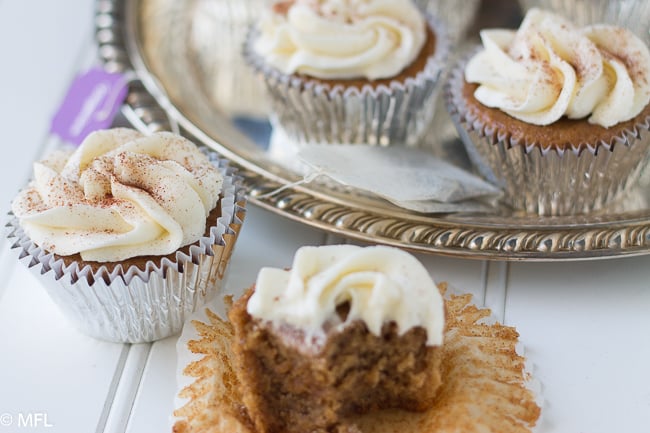 cupcakes on top of and in front of silver platter with cupcake in front half eaten