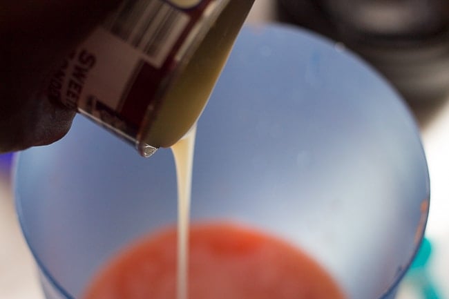 condensed milk being poured. This Jamaican Style Carrot Juice Recipe is authentic and delicious! Perfect recipe for a hot summer day. #jamaicanrecipe #carrotjuice #condensed milk #juicerecipes