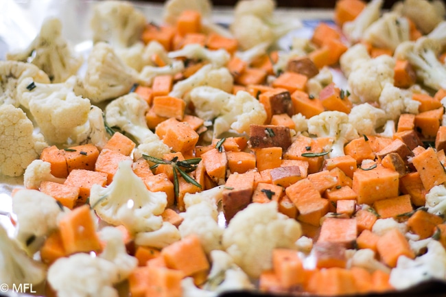 cauliflower sweet potato and rosemary on baking sheet