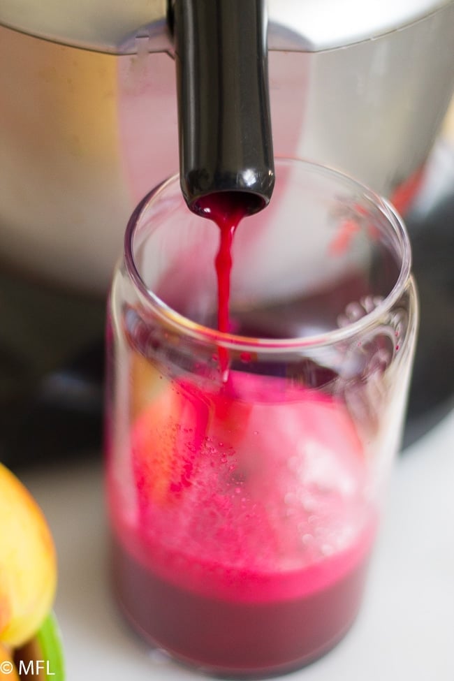 beet juice being poured into glass from juicer