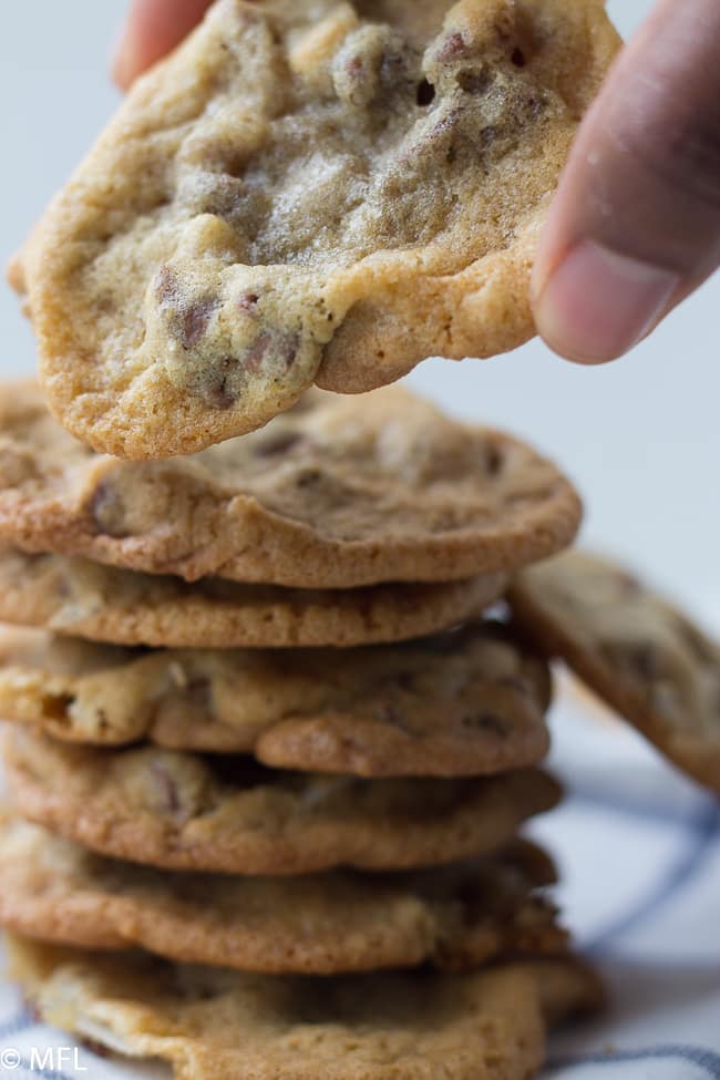 hand picking up chocolate chip cookie from stack of chocolate chip precan cookies