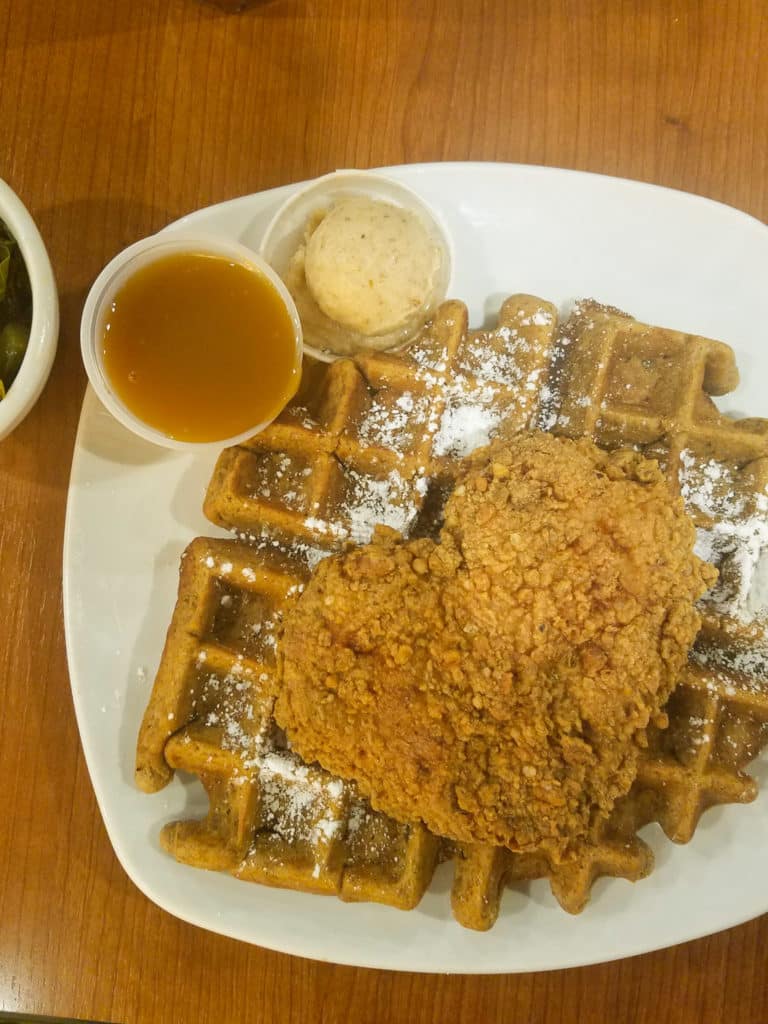 dame's chicken and waffles on white plate with sauce and butter on side