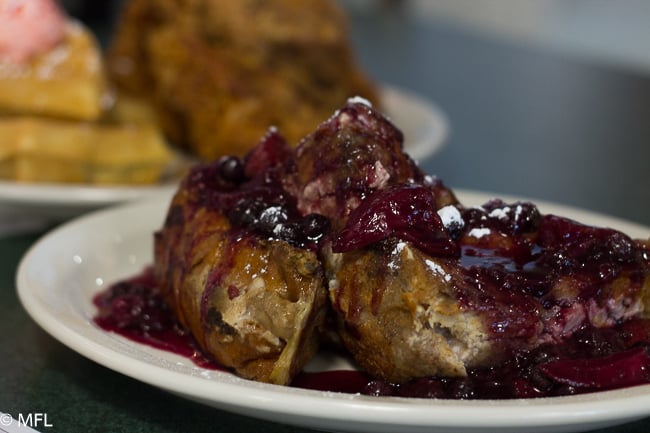 yo hala square on white plate covered in berry compote