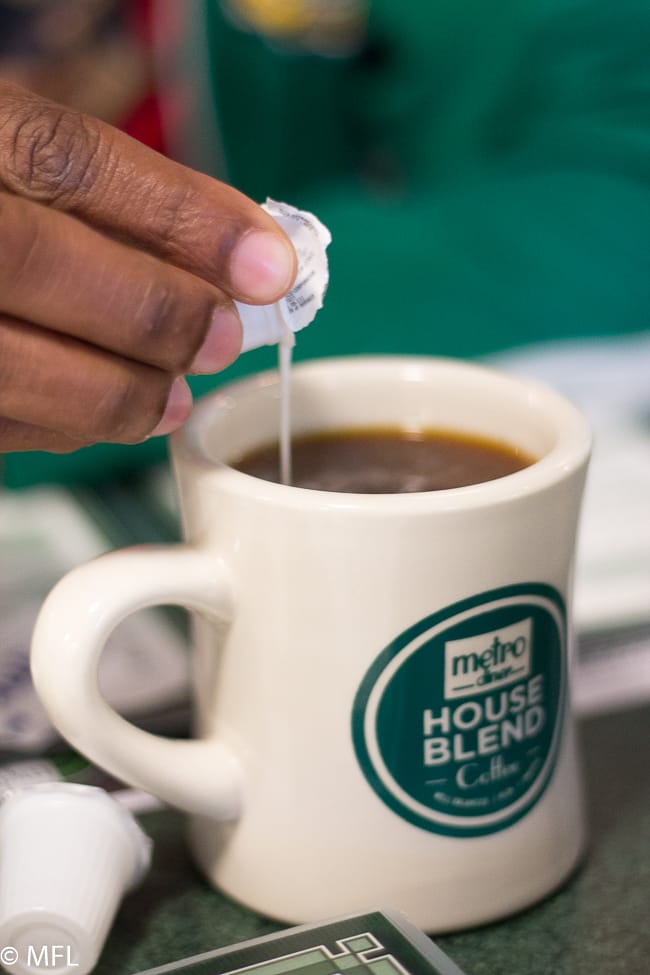 hand pouring creamer packet into coffee