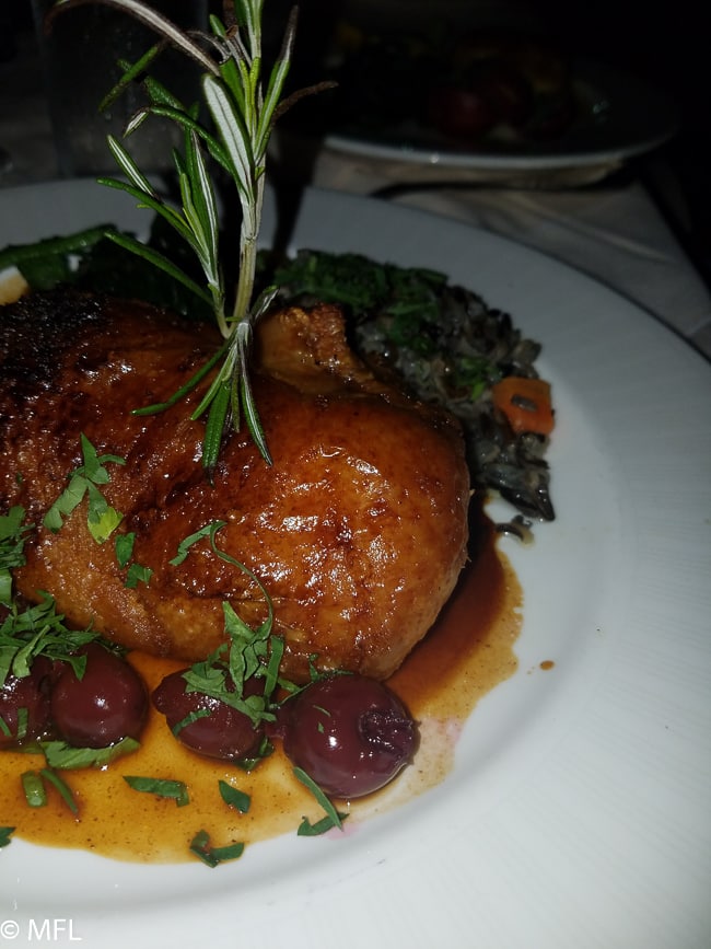 duck with olives and rosemary on white plate