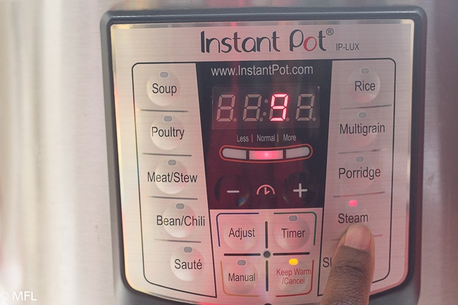 finger pressing steam button in instant pot and the number 9 on display