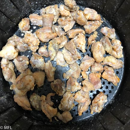 finished fried chicken pieces in air fryer basket