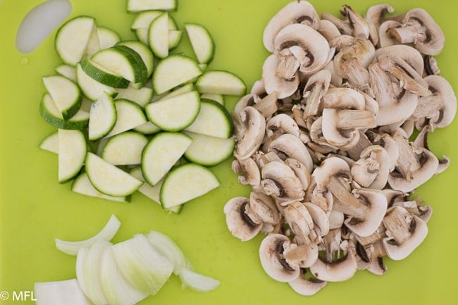 chopped zucchini, mushrooms, and onions on cutting board