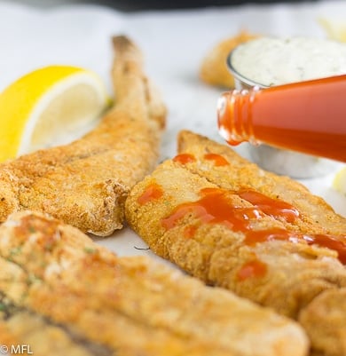 fried fish being covered in hot sauce