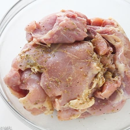 Raw chicken for instant pot chicken and rice covered in seasoning