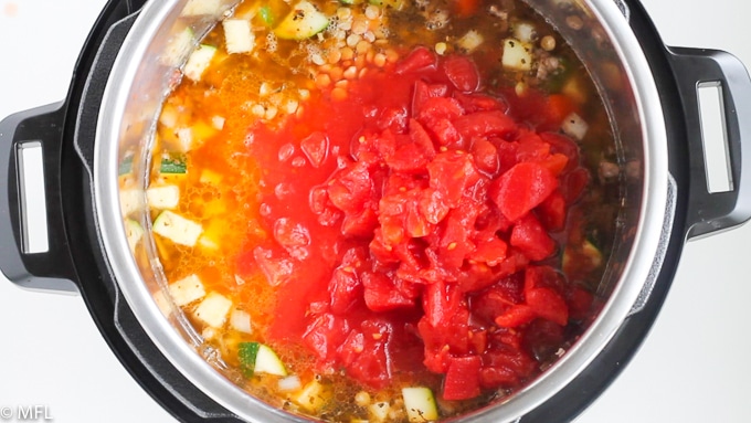 pressure cooker lentil soup in instant pot with tomatoes layered on top. 