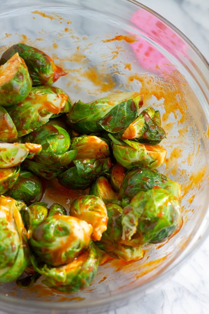 raw brussels sprouts in glass bowl covered in sauce