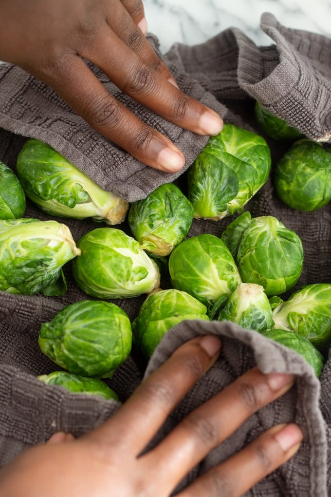 air fryer brussels sprouts in a towel with hands drying them