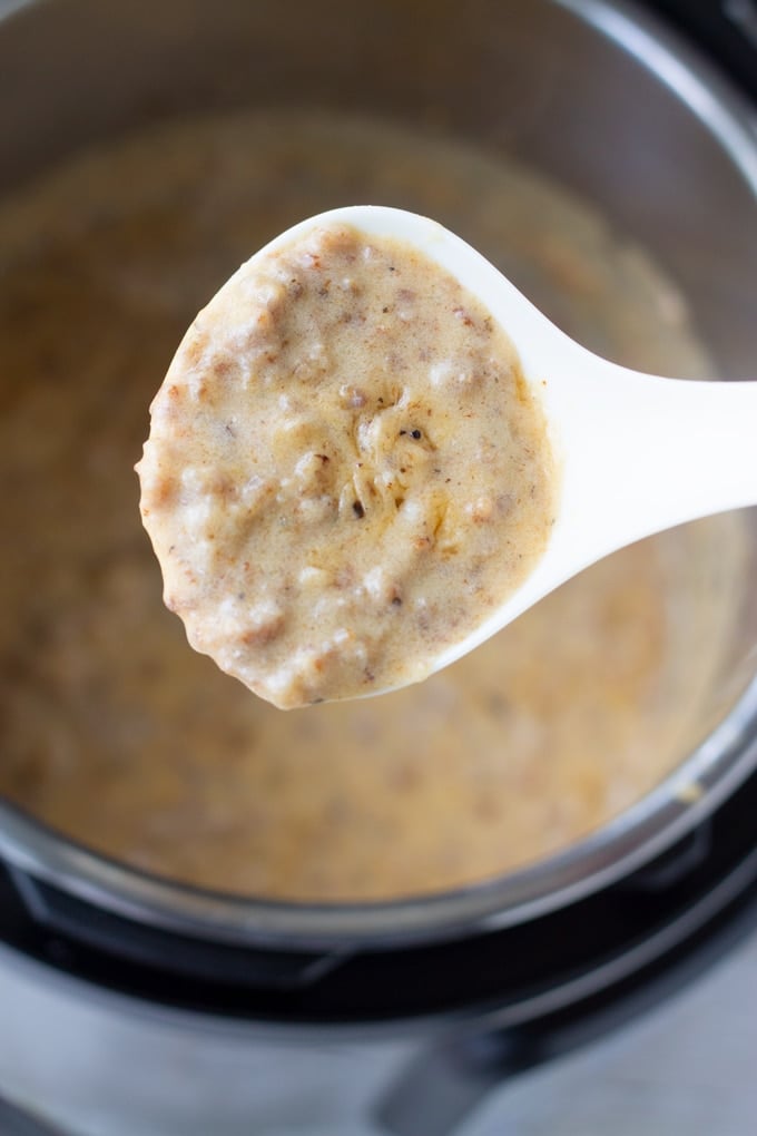 white sausage gravy on a spoon over instant pot