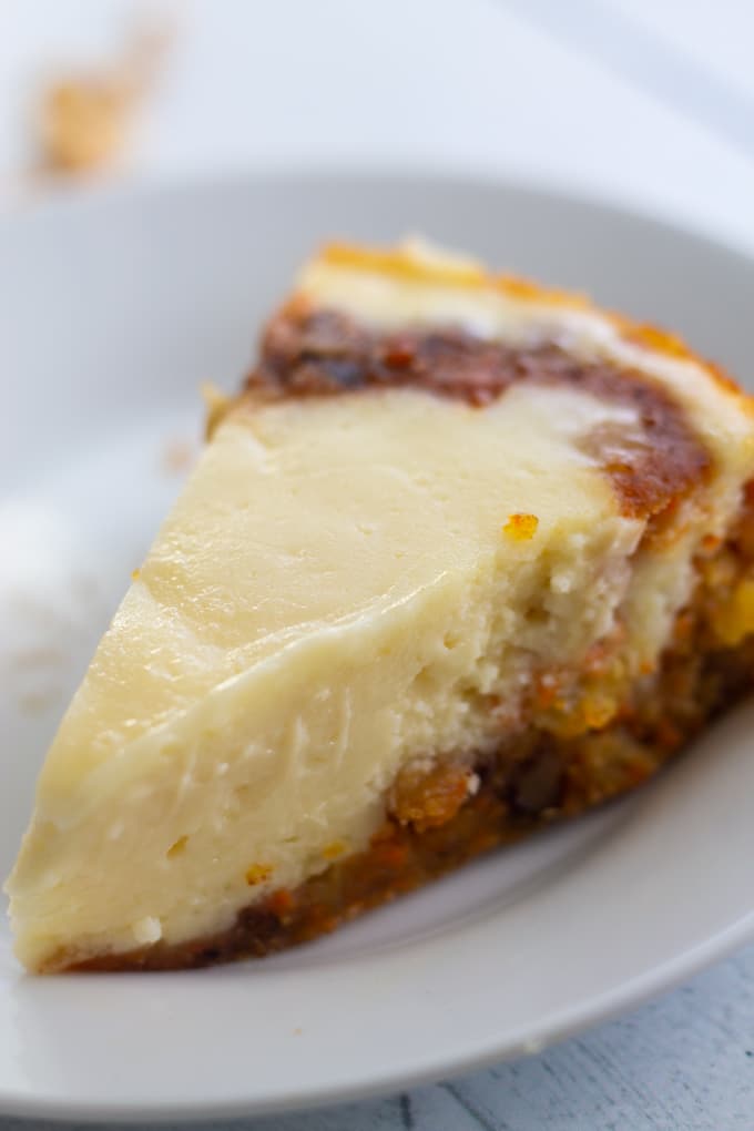 Delicious Instant Pot Carrot Cake Cheesecake is so easy to make. Get the best of both worlds with delicious and moist carrot cake and creamy cheesecake made in your Instant Pot Pressure Cooker. #instantpotcake #holidaybaking #recipe #cheesecakerecipe slice of instant pot cake on a plate