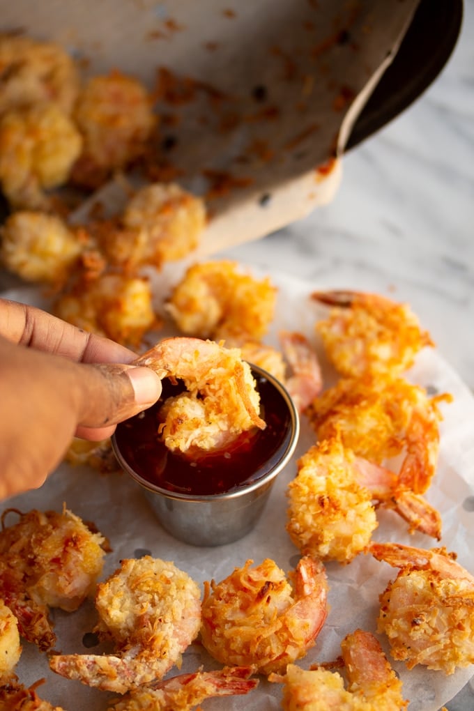 hand dipping air fryer shrimp in thai sweet chili sauce