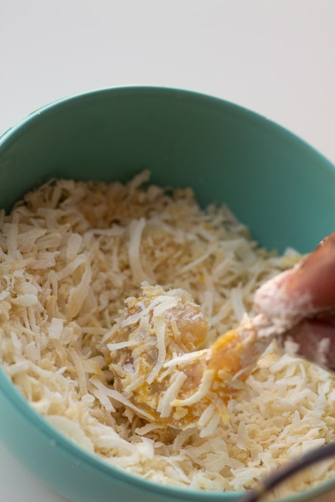 shrimp being dipped in shredded coconut and panko breadcrumb