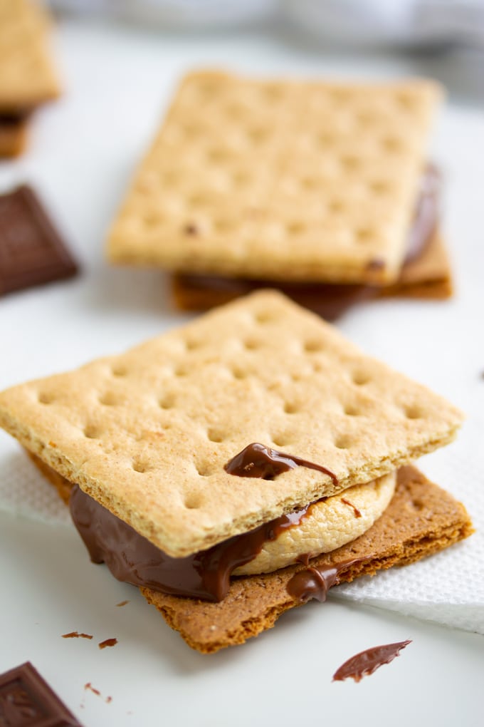You won’t need a campfire to make these s’mores, all you need is an Air Fryer. Delicious roasted marshmallows roasted right in the Air Fryer in less than 10 minutes. It’s the perfect easy dessert. #smallbatchdessert #airfryer #airfryerrecipes #airfryerrecipesfordessert #dessertrecipes air fryer s'mores on a napkin