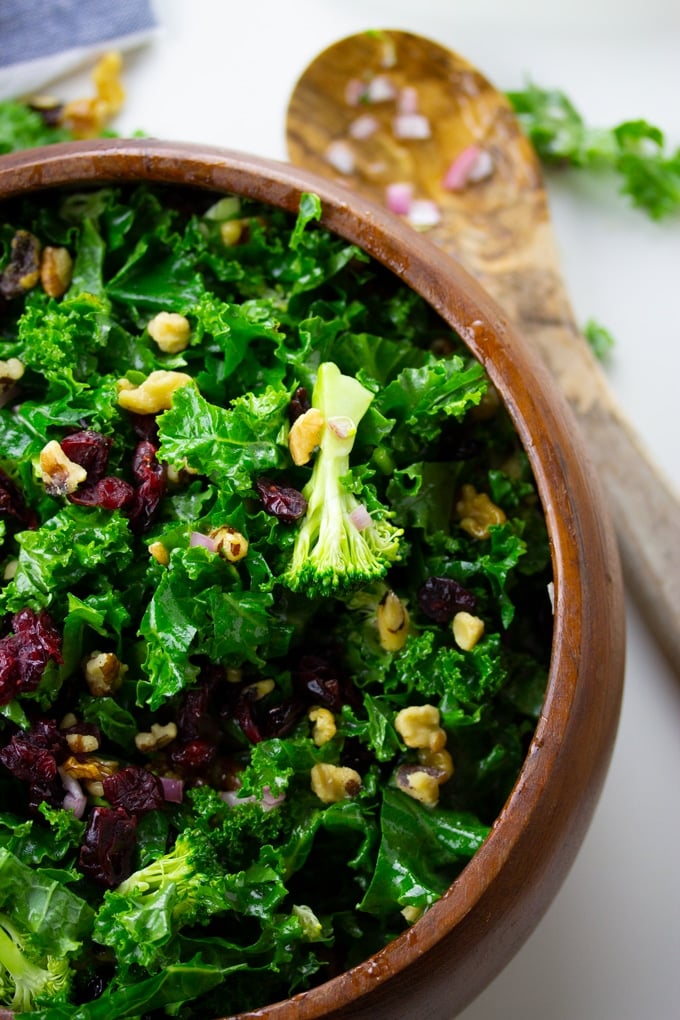 kale and broccoli salad in wooden bowl with wooden spoon to side