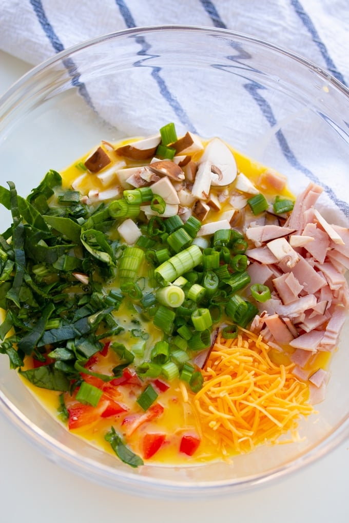 onions, vegetables, and ham in bowl on top of eggs