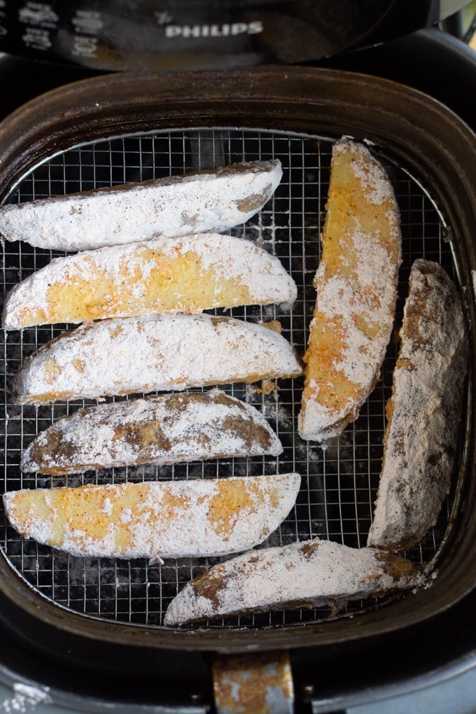 floured potato wedges in air fryer basket