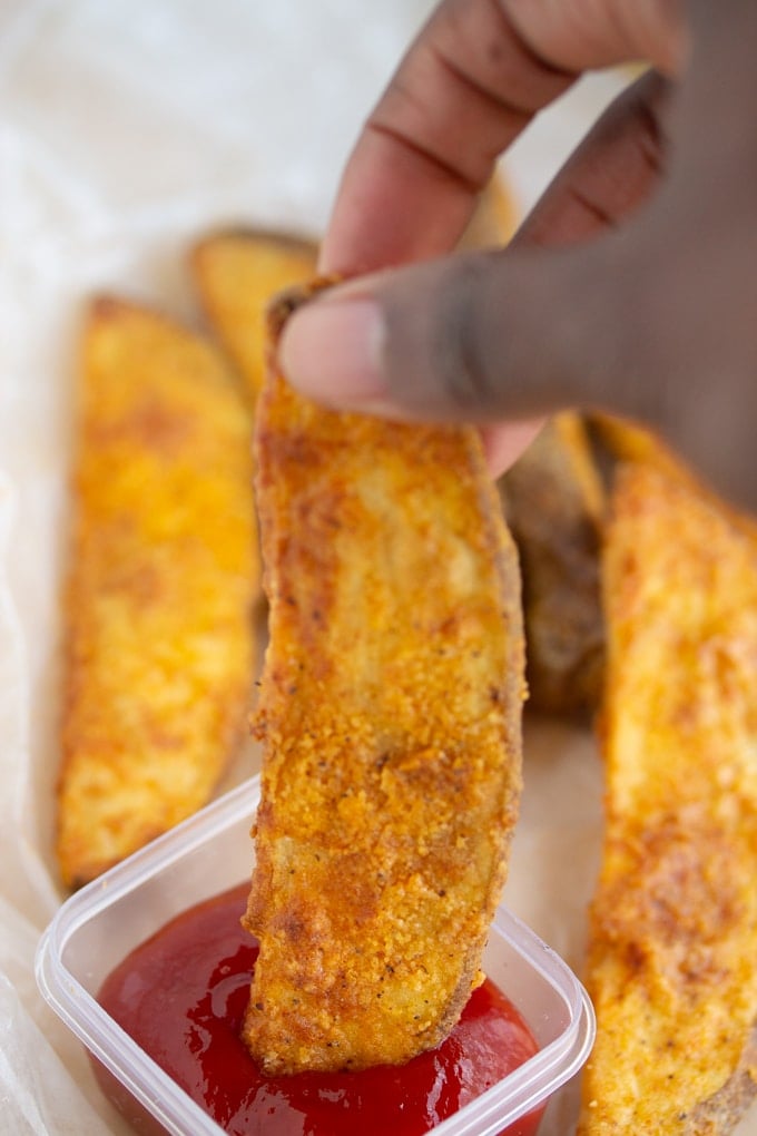 air fryer potato wedge being dipped in ketchup