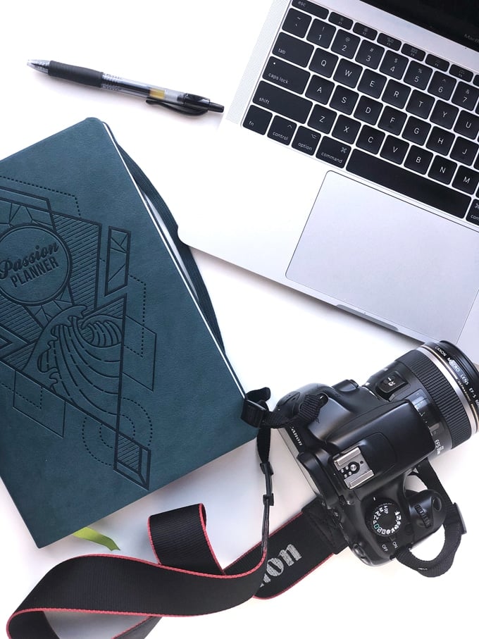 planner, laptop, and dslr camera on white board