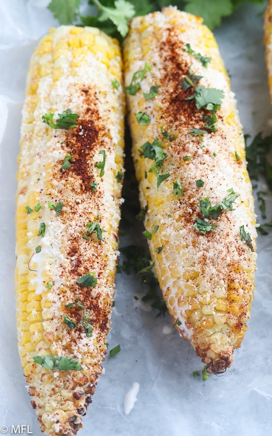 roasted corn covered with crema and cheese and chili powder