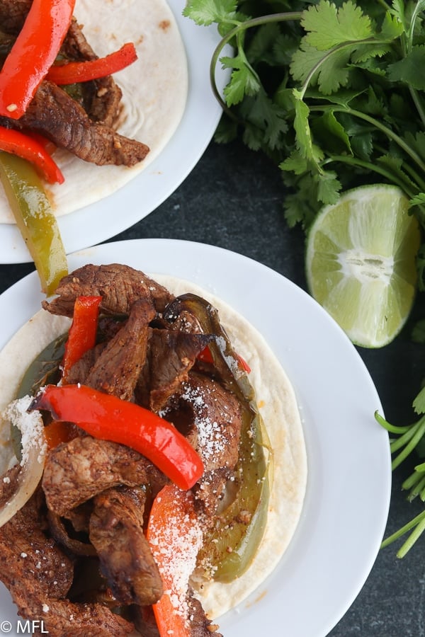 air fryer steak fajita on a plate with cilantro and lime on the side