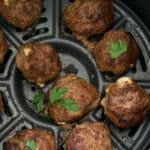meatballs in air fryer basket with some parsley on top