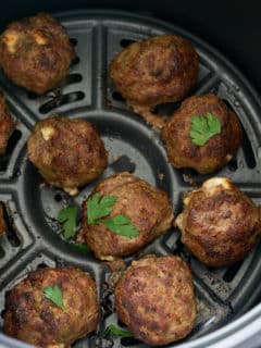 meatballs in air fryer basket with some parsley on top