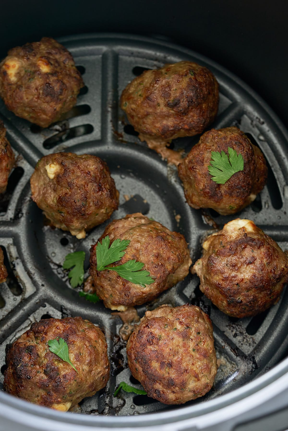 meatballs in air fryer basket with some parsley on top