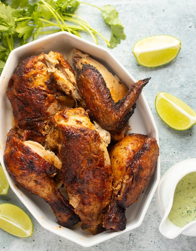 air fryer whole chicken cut with lime and cilantro surrounding it