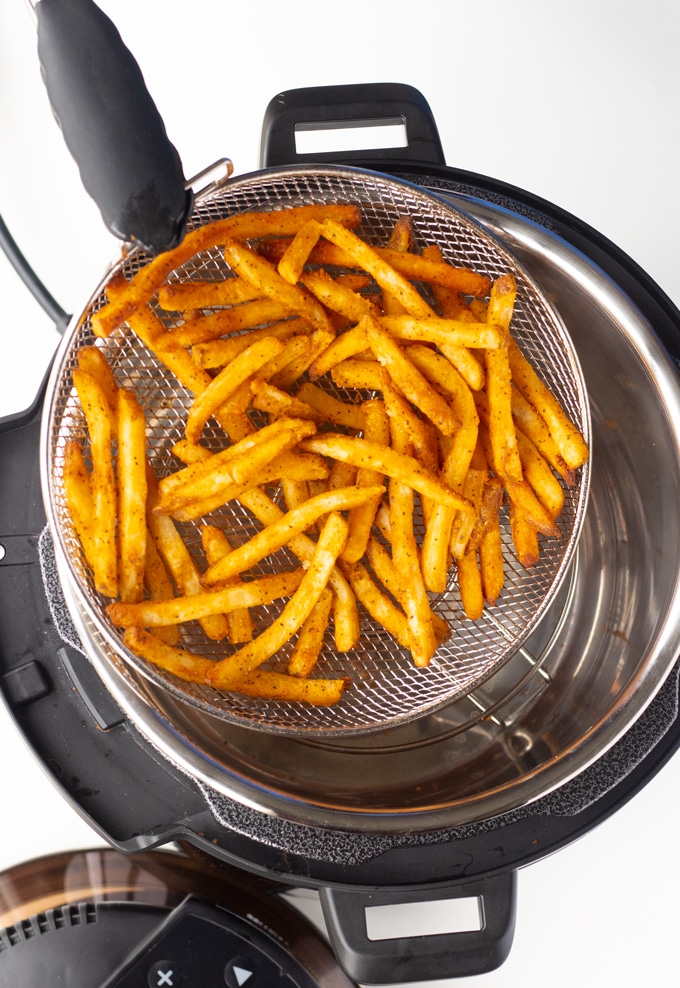 tongs removing fries from mealthy crisp lid basket