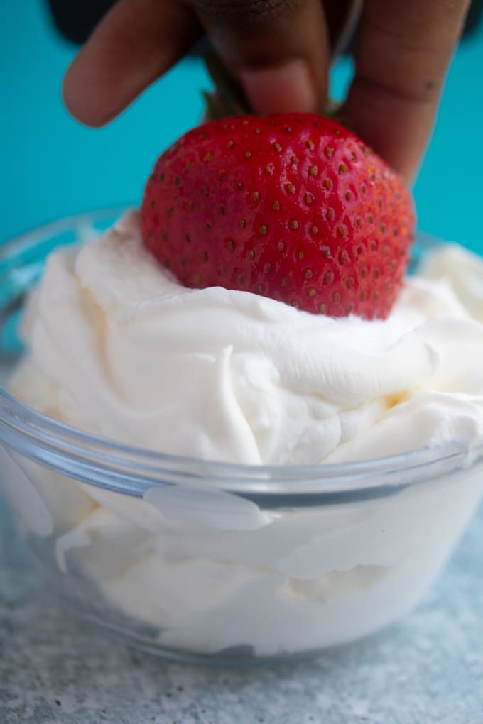 strawberry being dipped into whipped cream