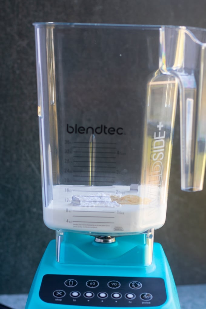 blendtec blender with heavy cream, powdered sugar, and vanilla inside of it