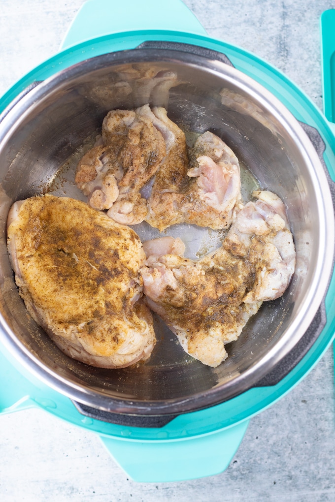 raw chicken pieces in instant pot being browned