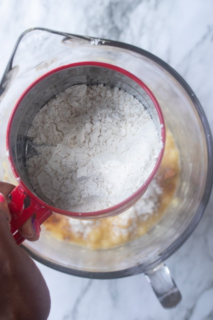 flour in sifter over bowl with mashed bananas