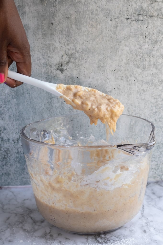 mashed banana fritter batter sliding of spoon into bowl