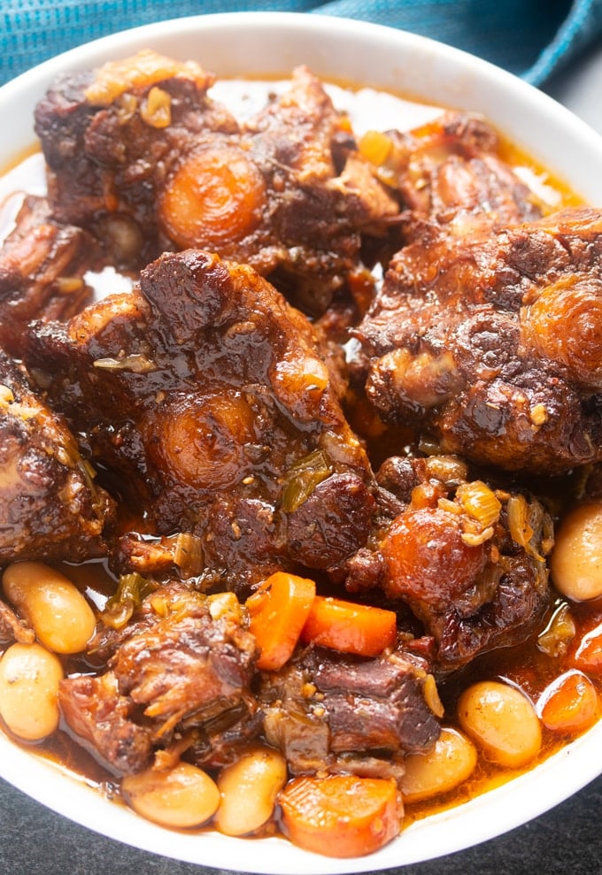 jamaican oxtail in a white bowl with blue napkin in background