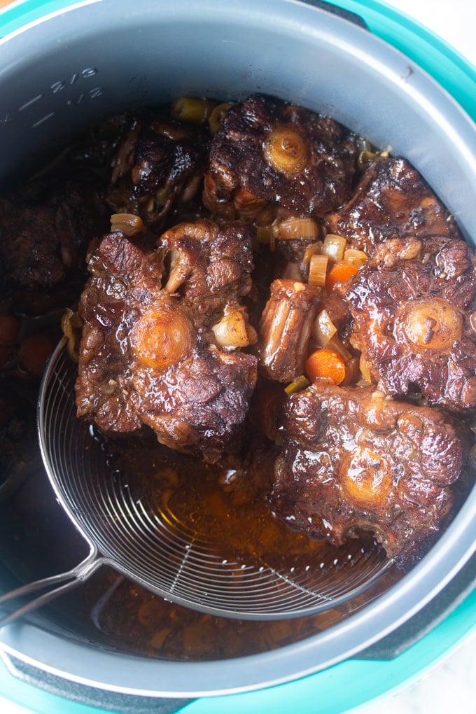 strainer removing oxtail pueces from instant pot