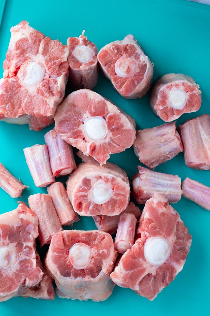raw oxtail pieces on a teal cutting board