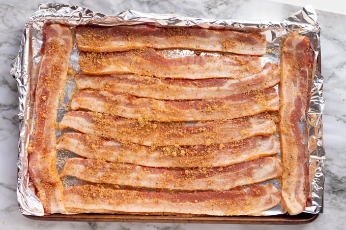 bacon laying on baking tray with brown sugar all over it