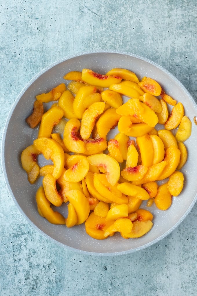 frozen peaches laying in a flat layer in a skillet